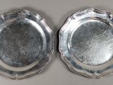 paire d'assiettes argentées aux bords festonnés sur fond blanc
