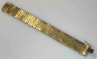 a close up of a gold bracelet on a white surface