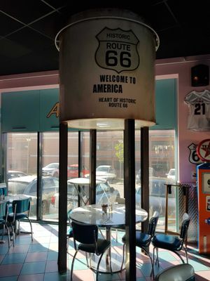 tables and chairs in a restaurant with a sign that says route 66 welcome to america
