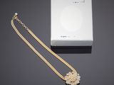 une boîte blanche ornée d'une chaîne en or et d'un pendentif en forme de fleur