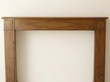 une photo d'une cheminée avec un manteau en bois dans une pièce blanche