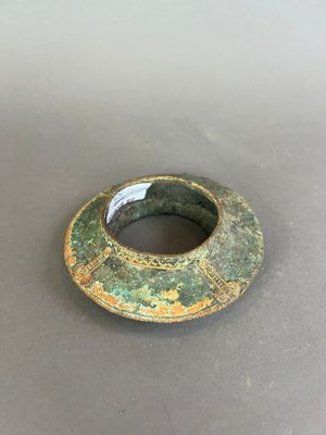 une photo d'une bague verte et dorée posée sur une table