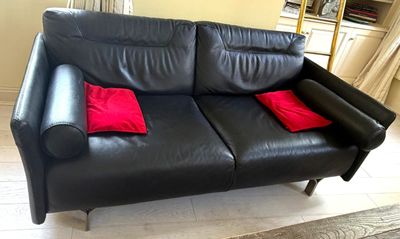 un canapé en cuir noir sur lequel sont posés deux coussins rouges