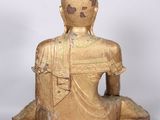 statue of a seated buddha sitting on a platform with a white background