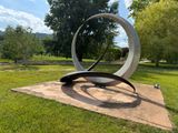 a metal sculpture in the middle of a grassy area