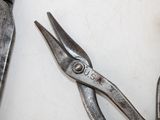 two pairs of pliers sitting on a white surface