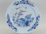 assiette bleue et blanche ornée d'un oiseau et de fleurs