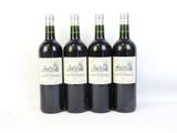 quatre bouteilles de vin sont alignées sur une surface blanche