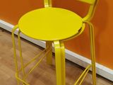 bright yellow metal stool against orange wall with wooden floor