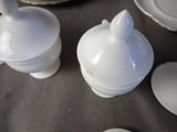 some white dishes are sitting on a table with a black table cloth