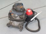 un aspirateur posé par terre à côté d'un bidon
