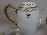 a white tea pot with gold trim and a cup and saucer