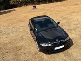 a black car parked in a field with trees in the background