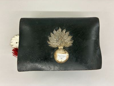 un petit sac à main noir orné d'un motif de feuilles dorées