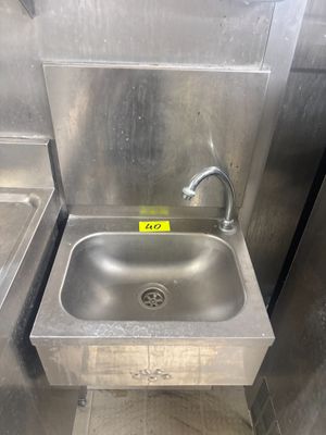 un évier en acier inoxydable dans le coin d'une toilette publique