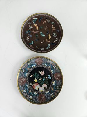 two decorative plates with flowers and butterflies on them on a white surface