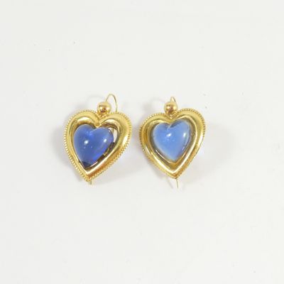 une paire de boucles d'oreilles en forme de cœur, dorées et bleues, sur fond blanc