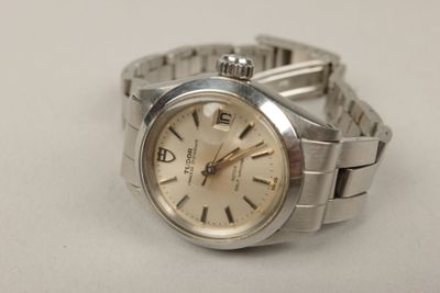 une montre en argent posée sur une surface blanche