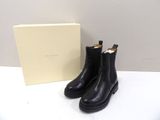 Les bottes noires sont à côté de la boîte, sur la table.