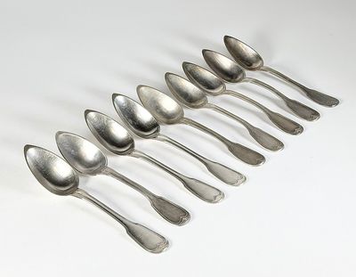 six cuillères en argent sont alignées sur une surface blanche