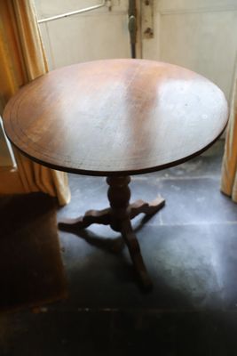 une table ronde au plateau en bois, placée devant une fenêtre