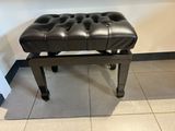 un banc en cuir noir posé sur un sol carrelé