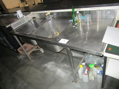 un évier en acier inoxydable dans une cuisine dotée d'un plan de travail noir