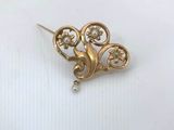 a close up of a gold brooch with pearls on a white surface