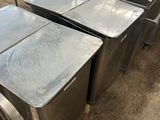 Plusieurs tables et chaises en acier inoxydable sont alignées dans un entrepôt