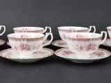 six cups and saucers are lined up on a black surface