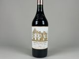 La bouteille de vin est posée sur la table, devant un fond gris.