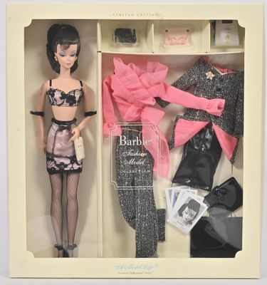 une poupée Barbie dans une boîte contenant des vêtements et des accessoires