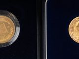 two gold coins are in a black box on a black surface