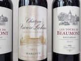 three bottles of red wine are lined up on a table