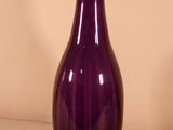 a purple glass vase sitting on a white surface