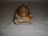 une petite horloge en or sur un socle en marbre sur une surface blanche