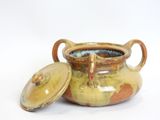 a brown pot with a lid sitting on a white surface
