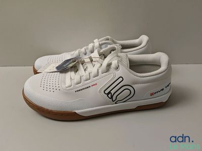white tennis shoes with a logo on the side of the shoe