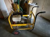 un petit chariot jaune sur lequel est posée une machine, dans un garage