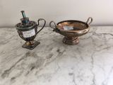 paire de vases plaqués argent, munis d'anses, posés sur une table en marbre