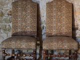 pair of antique upholstered chairs in front of a stone wall