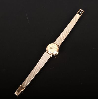 une montre en or posée sur une surface noire, avec un fond noir