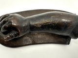 sculpture en bronze représentant une main posée sur une plaque en bois
