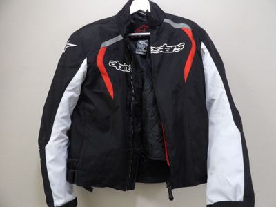 une veste noire et blanche rehaussée de touches de rouge, suspendue à un cintre