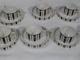 huit tasses à café et soucoupes posées sur une nappe blanche