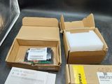 plusieurs cartons contenant différents types d'équipements électroniques posés sur une table