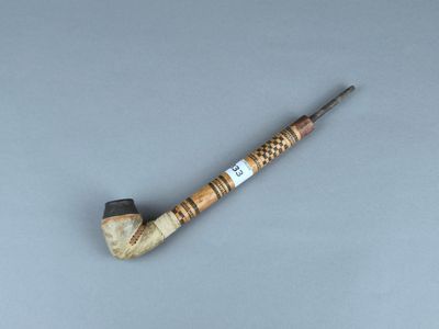 une vieille pipe avec un tuyau en bois posée sur une surface grise