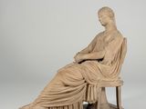 statue of a woman sitting on a bench with a book in her lap