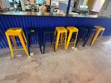 quatre tabourets jaunes posés devant un bar orné d'un rideau bleu