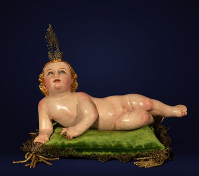 a statue of a baby laying on a green pillow